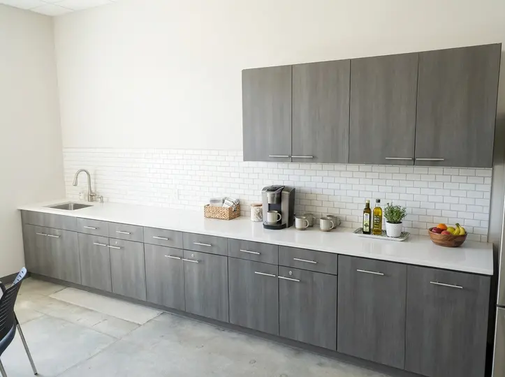 Modern grey laminate kitchen run with white counters, subway-tile backsplash and integrated appliances