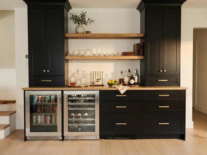 Black shaker home bar with brass pulls, floating wood shelves, glassware and dual glass-front beverage fridges
