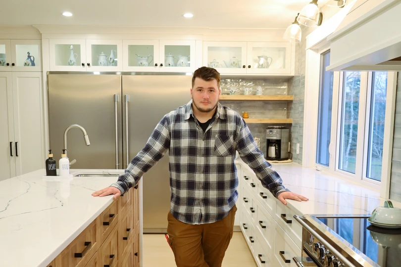 King Cabinetry owner in a custom white kitchen with marble countertops and stainless steel appliances